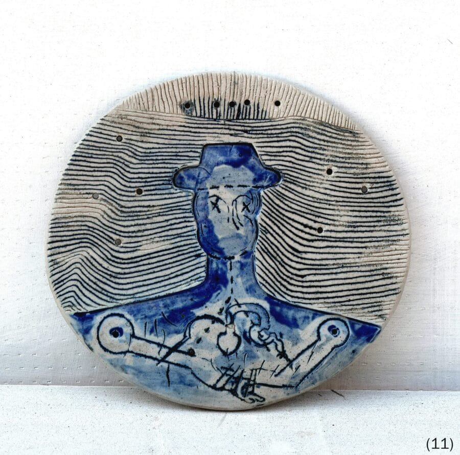 Round ceramic plate with concentric incised lines and blue-glazed hat figure with mechanical arms by Luis Mandiola