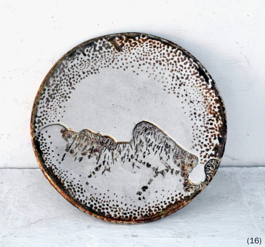 Round ceramic plate with speckled brown border and incised mountain landscape by Luis Mandiola